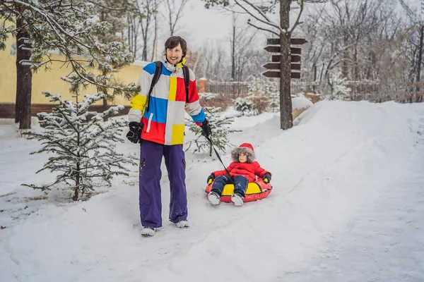Papà e figlio si divertono sulle tubature in inverno. Divertimento invernale per tutta la famiglia — Foto Stock