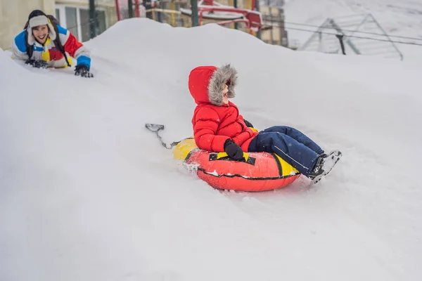 Criança se divertindo no tubo de neve. O rapaz está a montar um tubo. Diversão de inverno para crianças — Fotografia de Stock