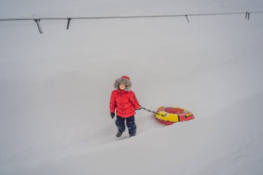 Çocuk kar tüpünde eğleniyor. Çocuk bir boruya biniyor. Çocuklar için kış eğlencesi