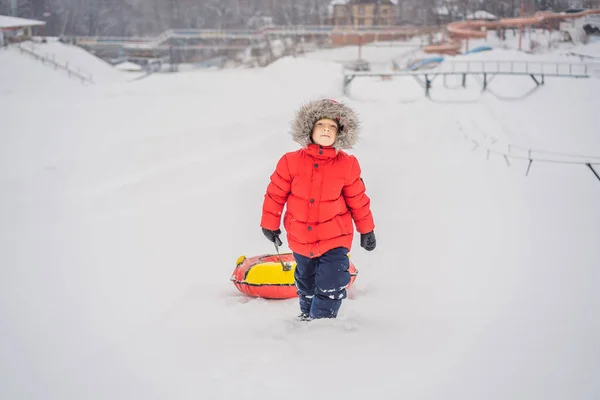 Niño divirtiéndose en tubo de nieve. El chico está montando un tubo. Diversión de invierno para niños — Foto de Stock
