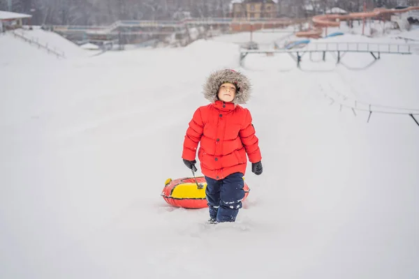 Bambino che si diverte sul tubo della neve. Il ragazzo sta cavalcando un tubo. Divertimento invernale per bambini — Foto Stock