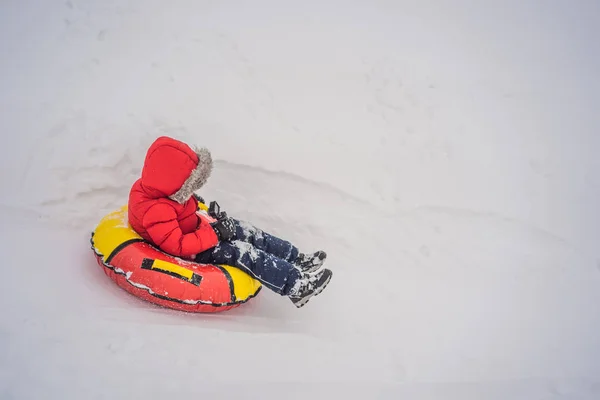 Dziecko bawiące się na snowtubie. Chłopak jedzie na rurze. Zimowa zabawa dla dzieci — Zdjęcie stockowe