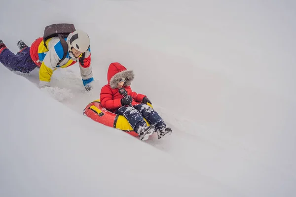 Papà e figlio si divertono sulle tubature in inverno. Divertimento invernale per tutta la famiglia — Foto Stock