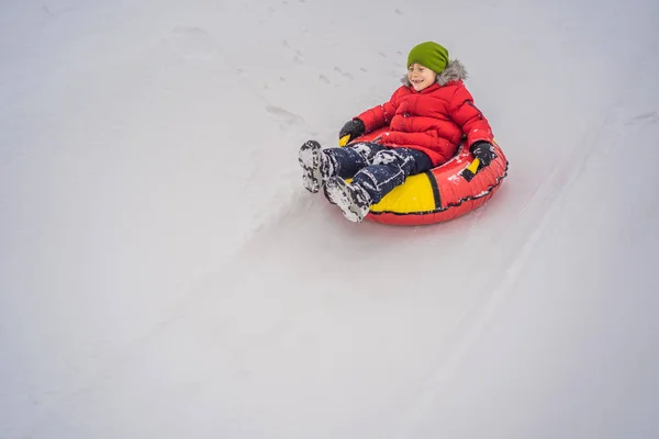 Das Kind hat Spaß auf der Schneekanone. Junge reitet auf einem Schlauch. Winterspaß für Kinder — Stockfoto