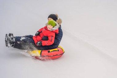 Anne oğul şişme bir kış kızağı borusuna biniyor. Tüm aile için kış eğlencesi