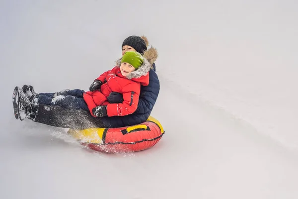 Matka syn jízda na nafukovací zimní sáně potrubí. Zimní zábava pro celou rodinu — Stock fotografie