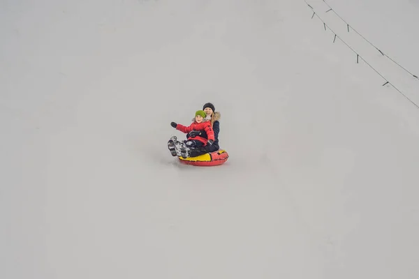 Mama syn jeździć na nadmuchiwane zimowe sanie rurki. Zimowa zabawa dla całej rodziny — Zdjęcie stockowe