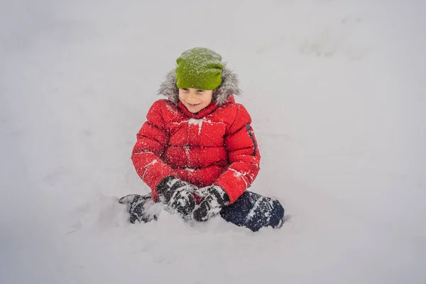 幸せな少年は雪と遊ぶ。冬の公園で雪を投げるかわいい子供。幸せな冬の休日。冬のファッション — ストック写真