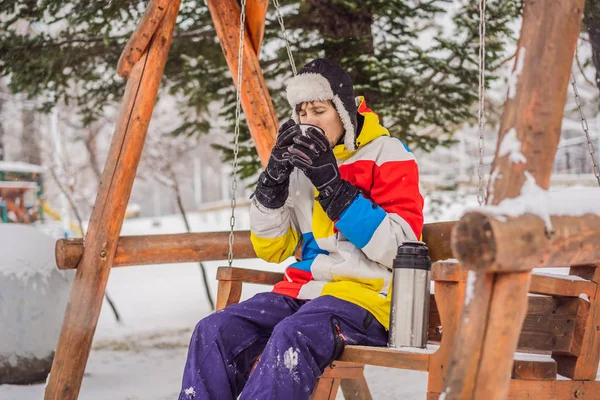 Snowboardos teát iszik egy termoszból egy síközpontban. — Stock Fotó