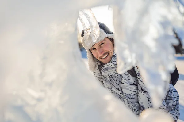 Krásný usmívající se mladý muž mezi ledem v zimě venku. Zimní koncept — Stock fotografie