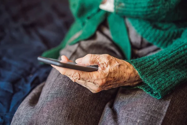 Mujer mayor usando el teléfono móvil mientras está sentada en el sofá — Foto de Stock