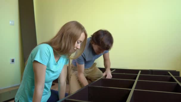 Νεαρή οικογένεια συναρμολογούν ένα ντουλάπι με ράφια — Αρχείο Βίντεο