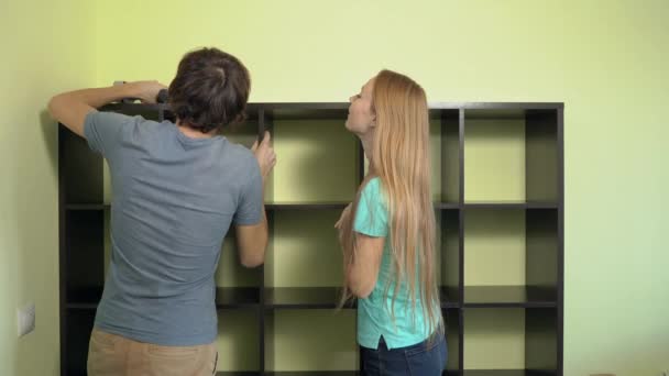 Junge Familie baut einen Schrank mit Regalen auf — Stockvideo