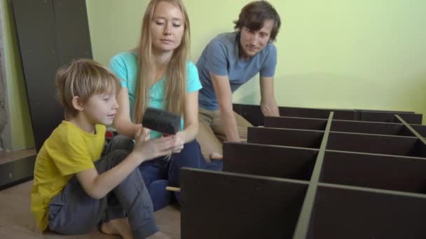 Νεαρή οικογένεια συναρμολογούν ένα ντουλάπι με ράφια — Αρχείο Βίντεο