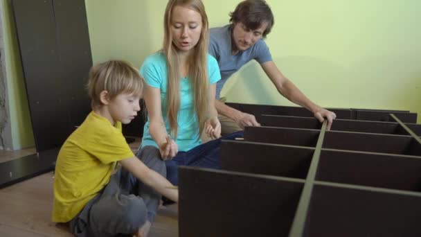 Молодая семья собирает шкаф с полками — стоковое видео