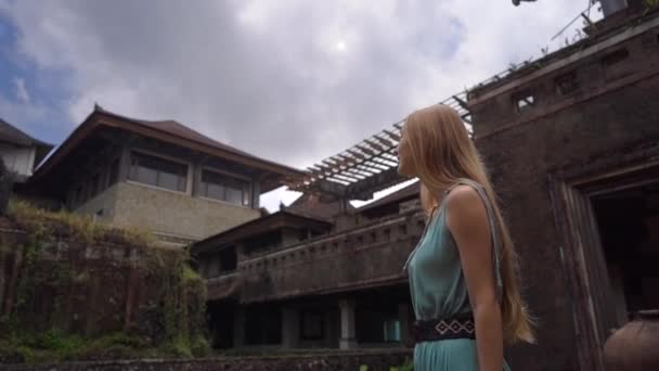 Slowmotion shot. Young woman tourist visits the abandoned and mysterious hotel in Bedugul. Indonesia, Bali Island. Bali Travel Concept — 비디오