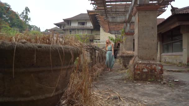 スローモーション撮影。若い女性の観光客は、ベドグルの放棄された神秘的なホテルを訪れます。インドネシア、バリ島。バリ旅行のコンセプト — ストック動画