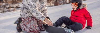 Babası oğluna snowboard öğretiyor. Kışın çocuklar için etkinlikler. Çocuklar kış sporu. HAYAT BANNER, BÖLÜM