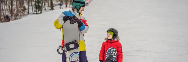 Ο δάσκαλος του snowboard μαθαίνει σε ένα αγόρι να κάνει snowboard. Δραστηριότητες για παιδιά το χειμώνα. Παιδικό χειμερινό άθλημα. Βάνερ τρόπου ζωής, μακρύς σχηματισμός — Φωτογραφία Αρχείου