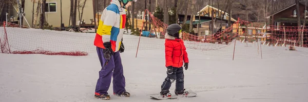 Instruktor snowboardu uczy chłopca jeździć na snowboardzie. Zajęcia dla dzieci w zimie. Zimowy sport dla dzieci. Lifestyle BANNER, LONG FORMAT — Zdjęcie stockowe