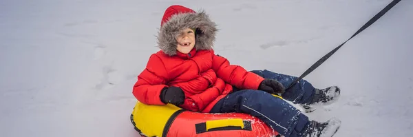 Niño divirtiéndose en tubo de nieve. El chico está montando un tubo. Diversión de invierno para niños BANNER, FORMATO LARGO —  Fotos de Stock