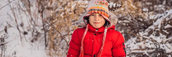 Pojke i röda kläder som leker utomhus. Aktiv fritid med barn på vintern under kalla dagar. Pojken har kul med första snön. Glad liten unge leker i snö, bra vinterväder Banner, Lång — Stockfoto