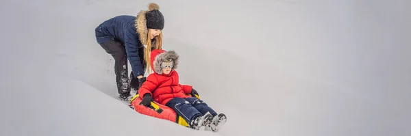 mom son ride on an inflatable winter sled tubing. Winter fun for the whole family BANNER, LONG FORMAT