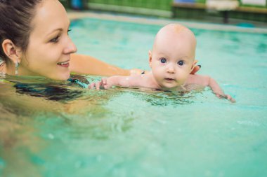 güzel anne kız şirin Bebek Yüzme havuzunda yüzmeyi öğretim. çocuk anne ile suda eğlenmek