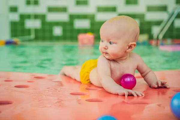 Hermosa madre enseñando linda niña cómo nadar en una piscina. Niño divirtiéndose en el agua con mamá — Foto de Stock