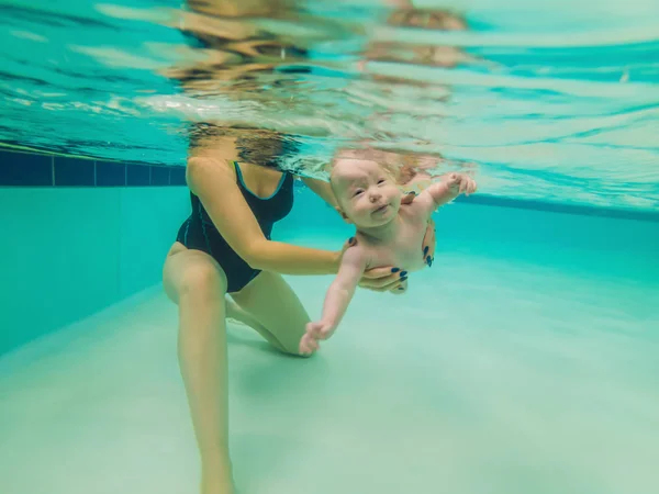 Schöne Mutter bringt süße Baby-Mädchen bei, wie man in einem Schwimmbad schwimmt. Kind vergnügt sich mit Mama im Wasser — Stockfoto