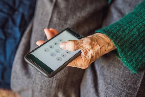 Старшая женщина с помощью мобильного телефона, сидя на диване — стоковое фото