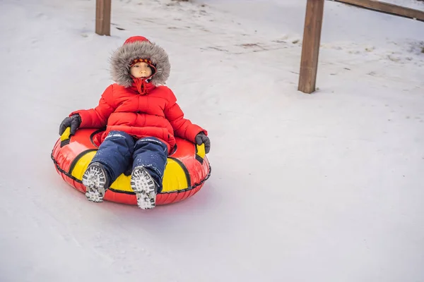 Dziecko bawiące się na snowtubie. Chłopak jedzie na rurze. Zimowa zabawa dla dzieci — Zdjęcie stockowe