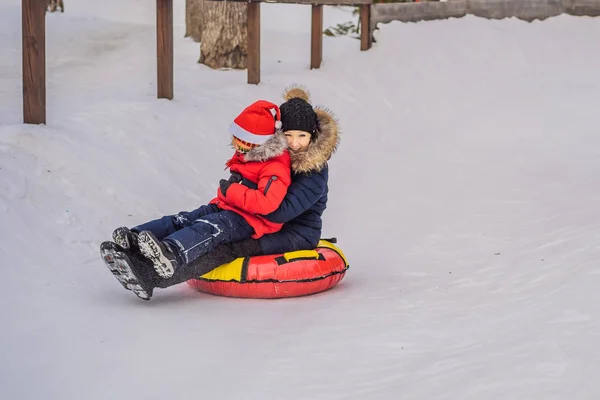 Matka syn jízda na nafukovací zimní sáně potrubí. Zimní zábava pro celou rodinu — Stock fotografie