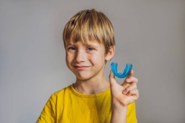 Six-year old boy shows myofunctional trainer. Helps equalize the growing teeth and correct bite, develop mouth breathing habit. Corrects the position of the tongue clipart