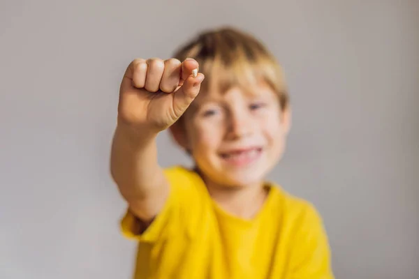 Litle menino caucasiano segura um dente de leite caiu entre os dedos e ri olhando para a câmera — Fotografia de Stock