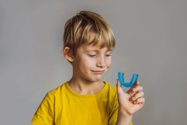 Un niño de seis años muestra un entrenador miofuncional. Ayuda a igualar el crecimiento de los dientes y la mordedura correcta, desarrollar hábito de respiración bucal. Corrige la posición de la lengua — Foto de Stock