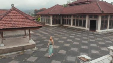 Bedugul 'daki terk edilmiş ve gizemli oteli ziyaret eden bir kadın turistin hava görüntüsü. Endonezya, Bali Adası. Bali Seyahat Konsepti