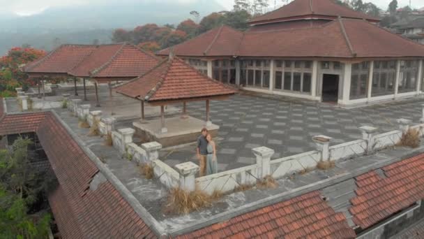 Aerial shot of a couple man and woman visiting the abandoned and mysterious hotel in Bedugul. Indonesia, Bali Island. Bali Travel Concept — Stock Video