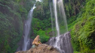 Genç kadın ve küçük oğlu turistler Bali adasındaki en büyük şelaleyi, Sekumpul şelalesini ziyaret ediyorlar. Bali konseptine Seyahat.
