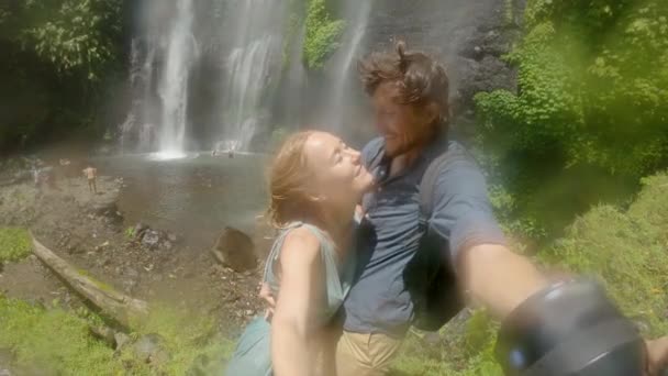 Um casal feliz de turistas visitar a bela cachoeira de Fiji na ilha de Bali. Viagem ao conceito de Bali — Vídeo de Stock