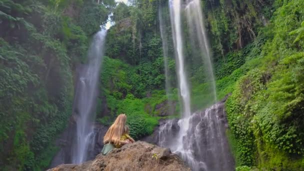 Die junge Frau und ihr kleiner Sohn besuchen den größten Wasserfall der Bali-Insel - den Sekumpul-Wasserfall. Anreise zum bali concept. — Stockvideo