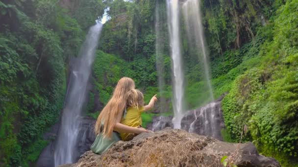 Young woman and her little son tourists visit the biggest waterfall on the Bali island - the Sekumpul waterfall. Travel to Bali concept. — Stockvideo