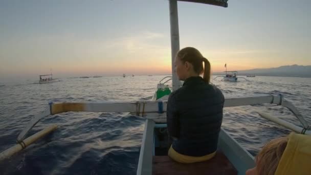 Familie rit in een Aziatische traditionele boot tijdens zonsopgang. Ze gaan dolfijnen zien in een baai van Lovina, in het noorden van Bali. Reis naar Bali concept — Stockvideo