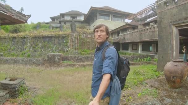 A fiatalember turista meglátogatja Bedugul elhagyatott és titokzatos szállodáját. Indonézia, Bali sziget. Bali utazási koncepció — Stock videók