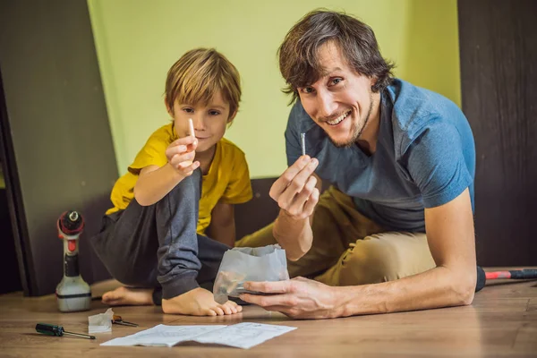 Padre e hijo ensamblando muebles. Un chico ayudando a su padre en casa. Concepto de familia feliz — Foto de Stock