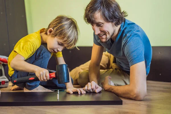 Otec a syn skládají nábytek. Chlapec pomáhající svému otci doma. Happy Family koncept — Stock fotografie