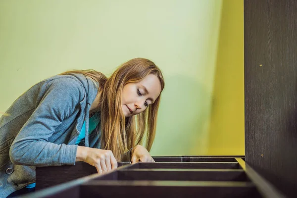 Caucasian woman using screwdriver for assembling furniture — Stok fotoğraf