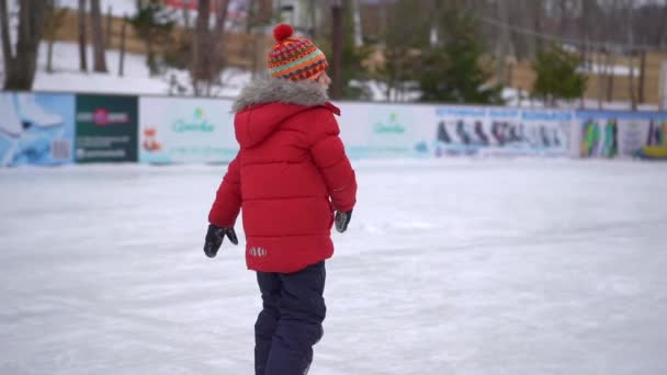 A jovem mãe e um rapazinho num ringue. O rapazinho aprende a patinar no gelo. Conceito de atividades de inverno — Vídeo de Stock