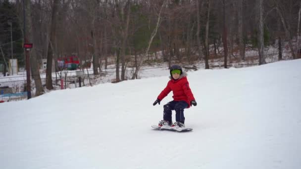 Mały chłopiec upada podczas pierwszej lekcji jazdy na snowboardzie. Koncepcja aktywności zimowej. Strzał zwolniony — Wideo stockowe