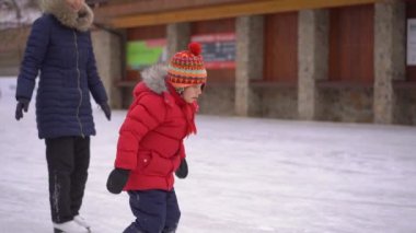 Genç bir anne ve küçük bir çocuk paten sahasında. Küçük çocuk buz pateni yapmayı öğrendi. Kış aktiviteleri konsepti